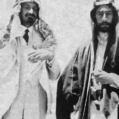 Dwóch mężczyzn w tradycyjnych arabskich strojach. Jeden z nich, Husajn, ma na sobie białą szatę i czarny krawat.