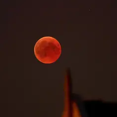 Krwawy księżyc 2026 w pełni, czerwony i tajemniczy, góruje nad ciemnym niebem, rzucając blask na zarys budowli.