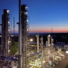 Wieczorna panorama kompleksu przemysłowego, symbolizującego postępującą industrializację. W oddali widać wiatraki.