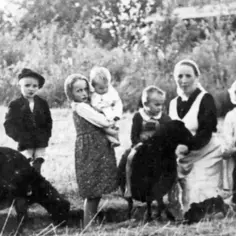 Rodzina Ulmów na tle natury. Dzieci bawią się z owcami, a matka czule opiekuje się najmłodszymi.
