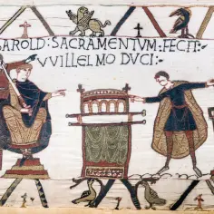 Tkanina przedstawia scenę z historii Anglii, gdzie król Harold składa przysięgę Wilhelmowi Zdobywcy, symbolizując początek nowej ery i system feudalizm.