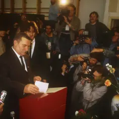 Lech Wałęsa wrzuca kartę do urny, otoczony przez dziennikarzy i fotoreporterów. To ważny moment dla III Rzeczypospolitej.