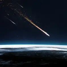 Jasny bolid przecina nocne niebo nad Ziemią, zostawiając za sobą smugę ognia i iskier.