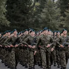 Żołnierze w zielonych beretach i mundurach maszerują w zwartym szyku. W rękach trzymają karabiny, gotowi do służby w swoim pułku.