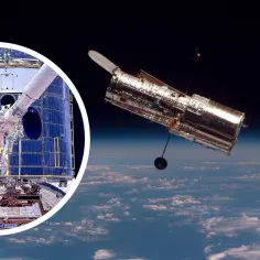 Astronauci serwisują teleskop Hubble'a na orbicie. Obok widać jego błyszczącą sylwetkę na tle Ziemi.