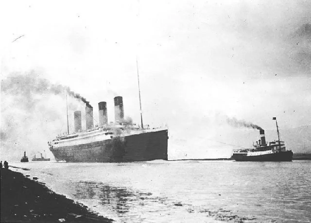 Wielki statek, który zatonął Titanic, holowany przez mniejszy statek. Dym unosi się z kominów.