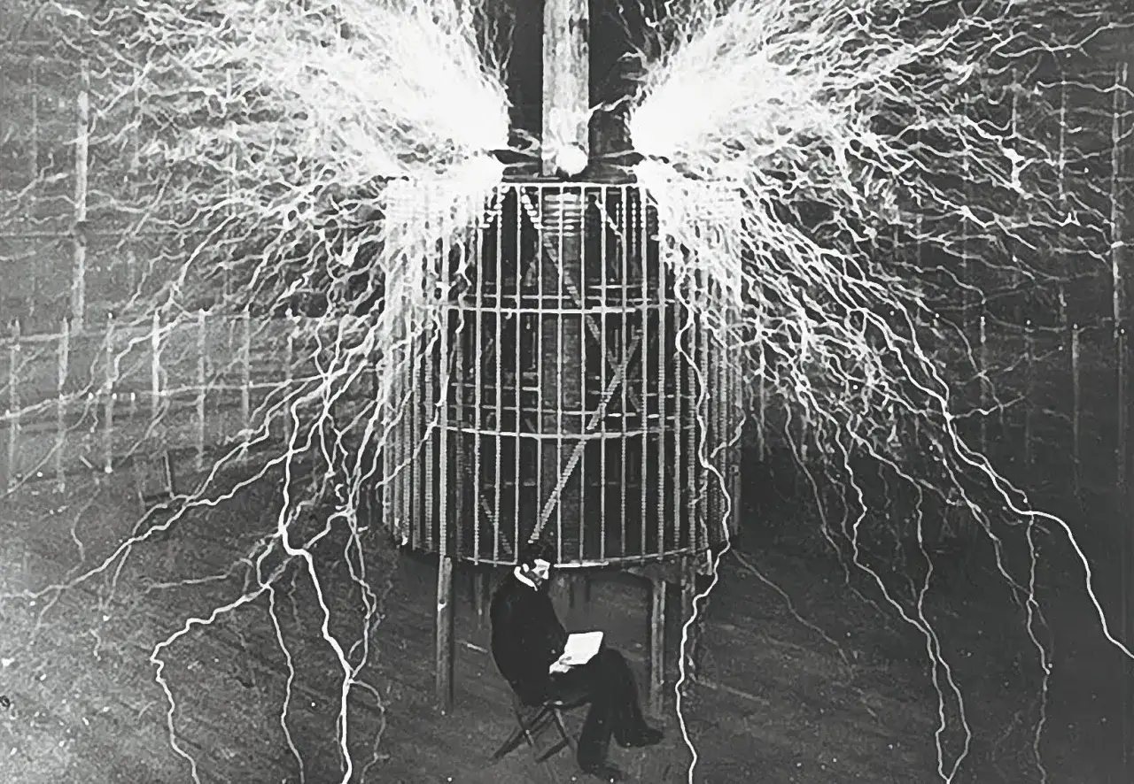 Nikola Tesla, siedzący w klatce, otoczony wyładowaniami elektrycznymi, które przypominają błyskawice. To on, a nie Edison, kto wymyślił prąd stały.