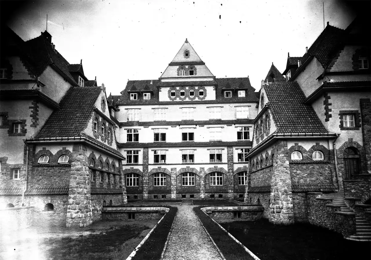 Dawny sanatorium, gdzie kiedyś zaczęto leczyć gruźlicę. Budynek z kamienia i cegły, z wieloma oknami i dachami.