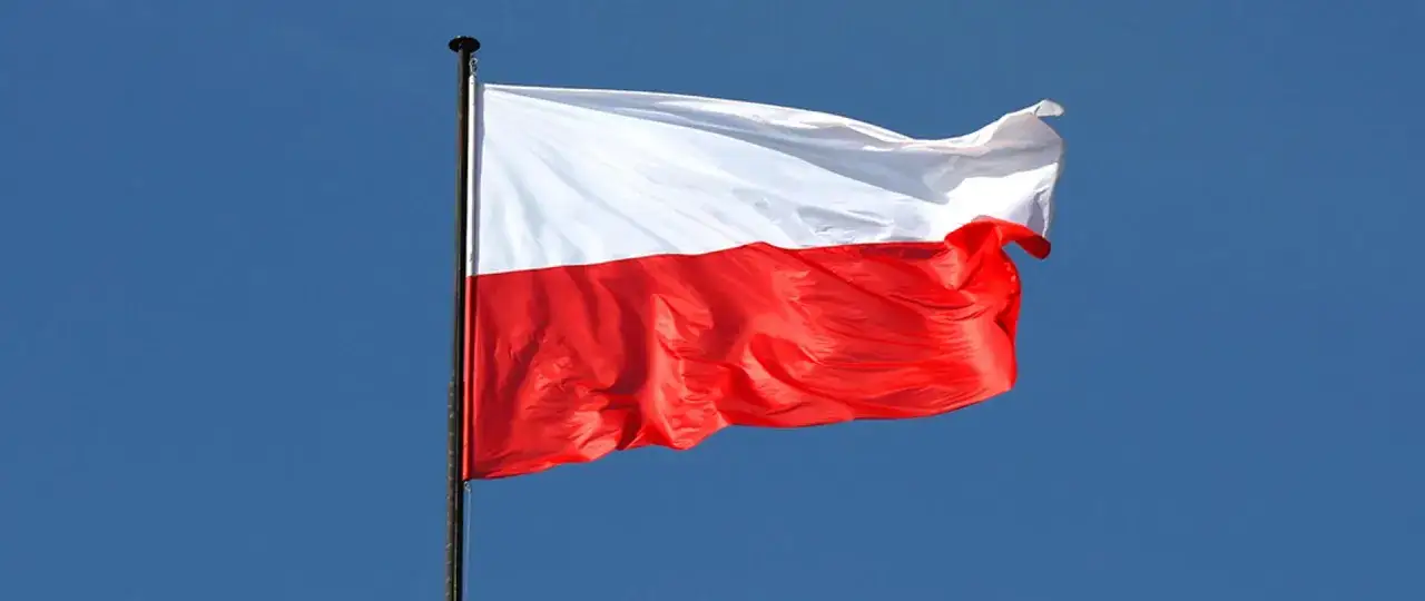 Biało-czerwona flaga Polski powiewa na maszcie na tle błękitnego nieba. Dziś 2 maja, świętujemy Dzień Flagi.