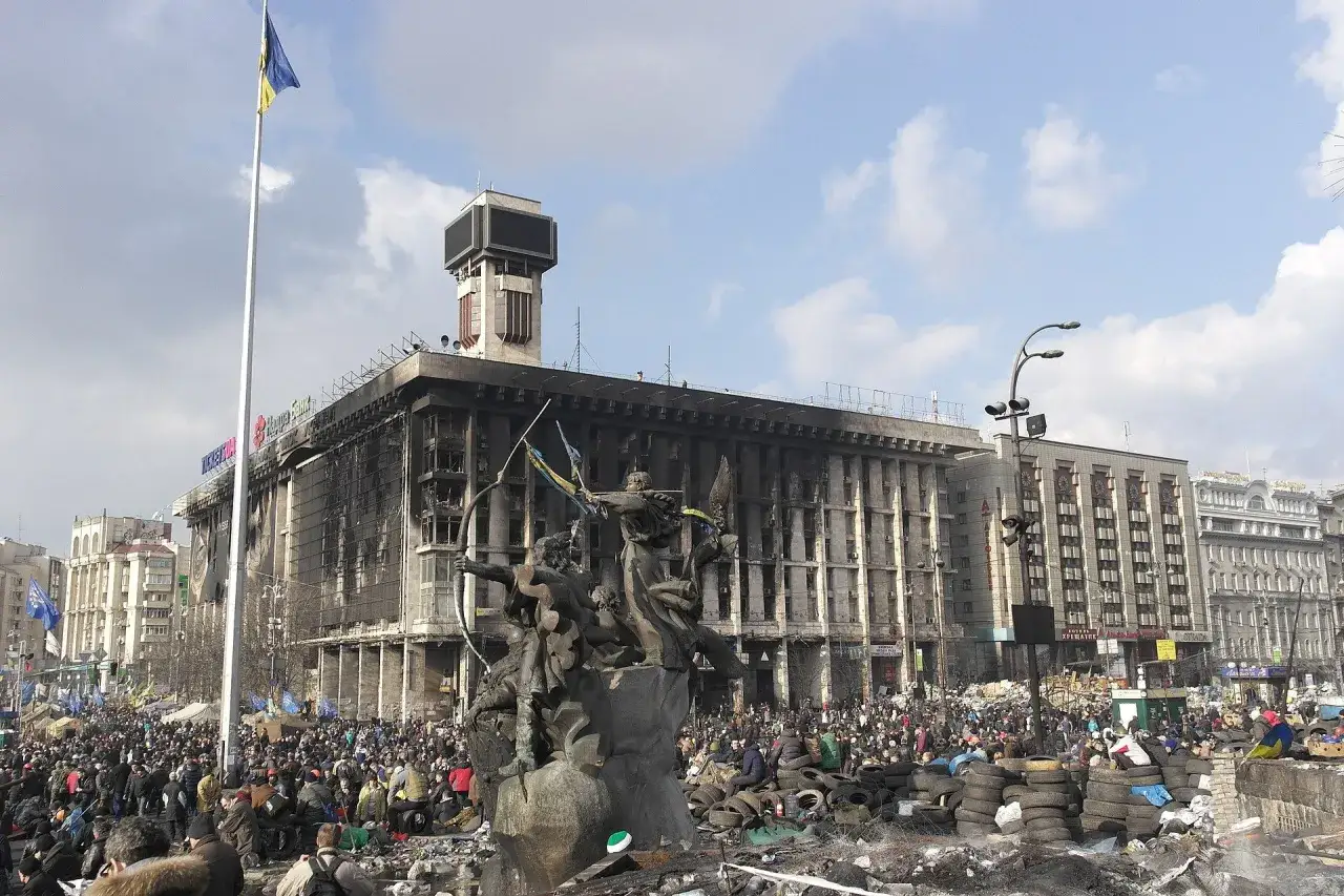 Majdan w Kijowie po zamieszkach, kiedy zaczęła się wojna na Ukrainie. Zniszczony budynek, tłumy ludzi, barykady z opon.